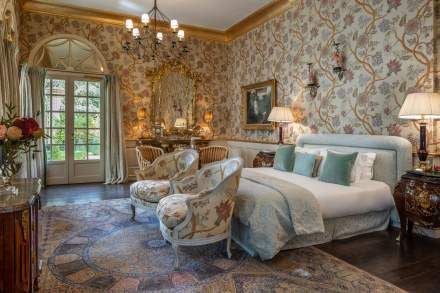 Elegant French Provence-style hotel room with soft blue walls, antique wooden furniture, and pristine white linens at Villa Gallici