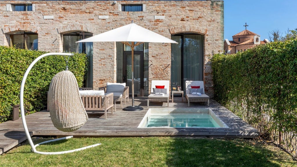 Elegant split-level loft suite with private pool, featuring modern furnishings, floor-to-ceiling windows, and lagoon views in Venice