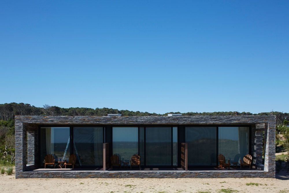 Minimalist bungalow at Bahia Vik resort, featuring sleek wood paneling, expansive windows, and a private terrace overlooking coastal Uruguay landscape