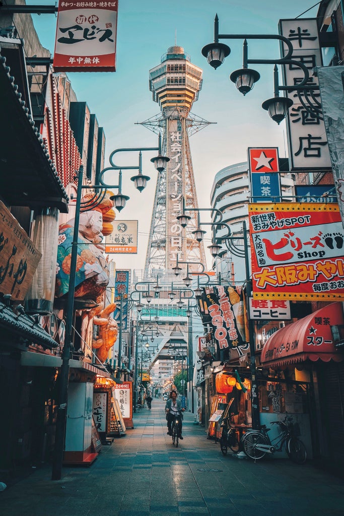 Illuminated traditional Japanese lanterns and vibrant neon signs along Dotonbori Street in Osaka at night, reflecting in canal waters