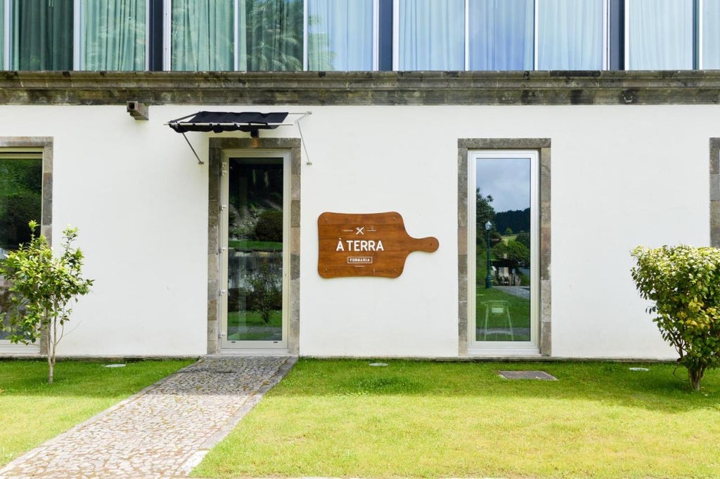 Modern luxury hotel building with floor-to-ceiling glass windows nestled among lush gardens, featuring a sleek white facade and scenic mountain backdrop