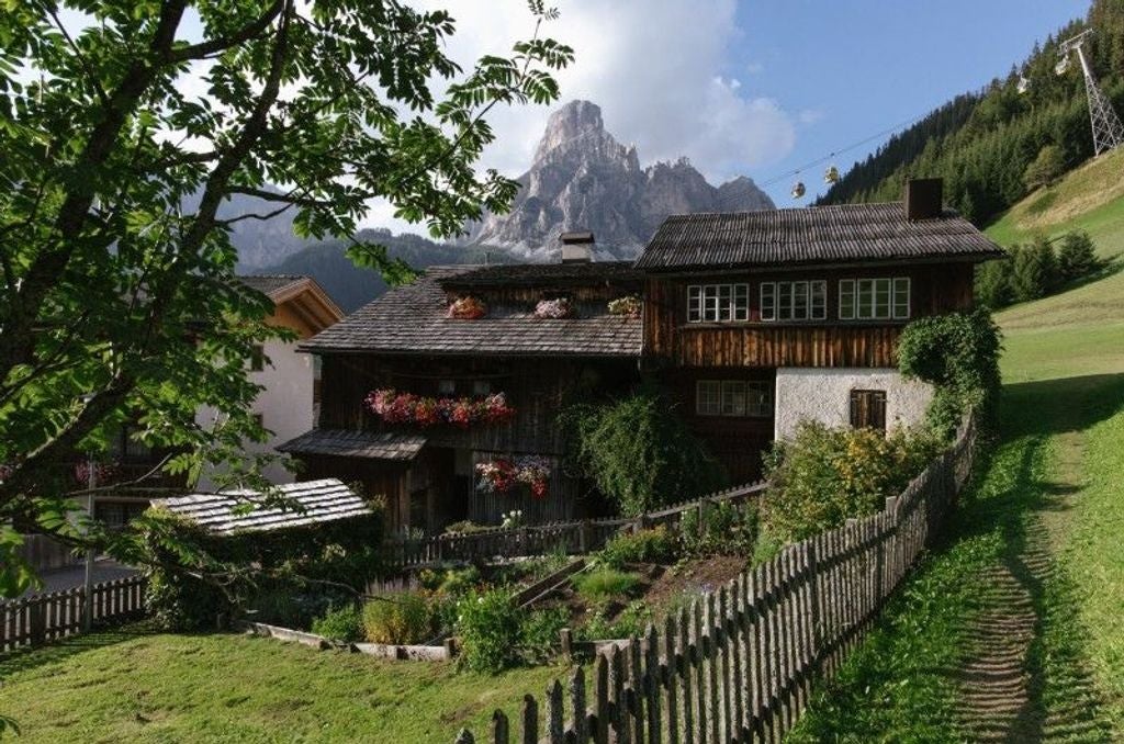 Luxurious mountain hotel La Perla with traditional alpine architecture, stone facade and wooden balconies nestled in snowy Corvara, Dolomites