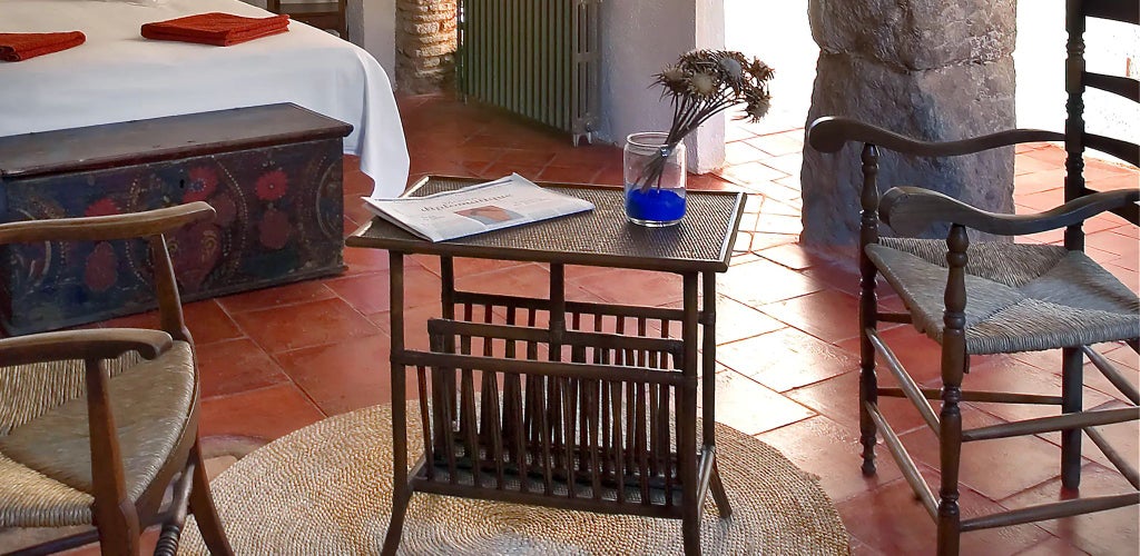 Rustic Spanish luxury suite with exposed wooden beams, elegant white linens, and warm terracotta tones in a historic cortijo-style bedroom setting