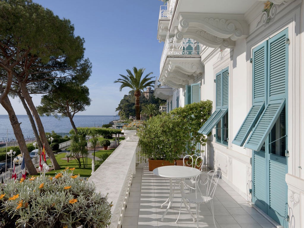 Elegant Mediterranean-style hotel with white facade and arched windows overlooking the Italian Riviera, surrounded by lush gardens