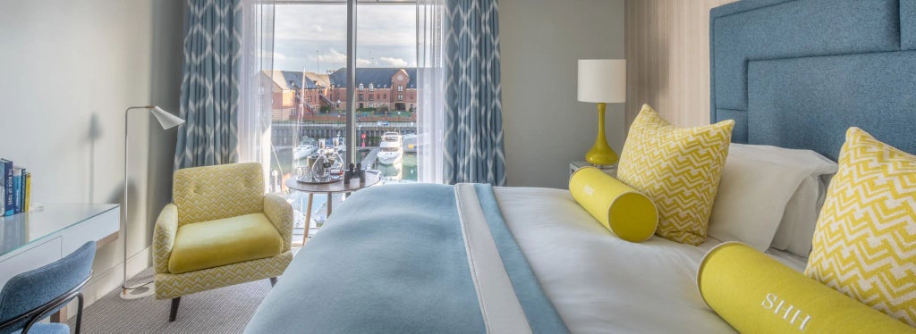 Spacious standard double room with modern decor, crisp white linens, elegant furnishings, and soft ambient lighting overlooking Southampton's waterfront