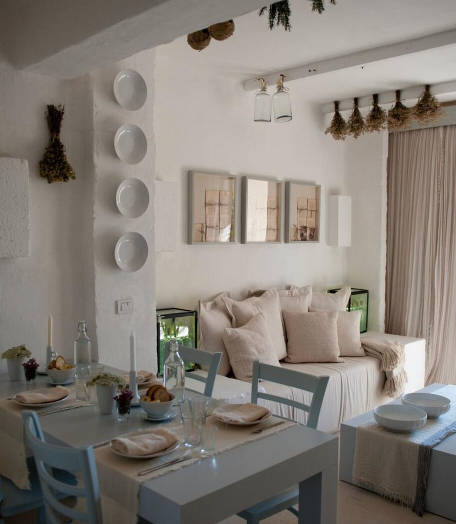 Elegant Mediterranean hotel room with vaulted stone ceiling, rustic chandelier, plush white bedding, and ornate wooden furnishings