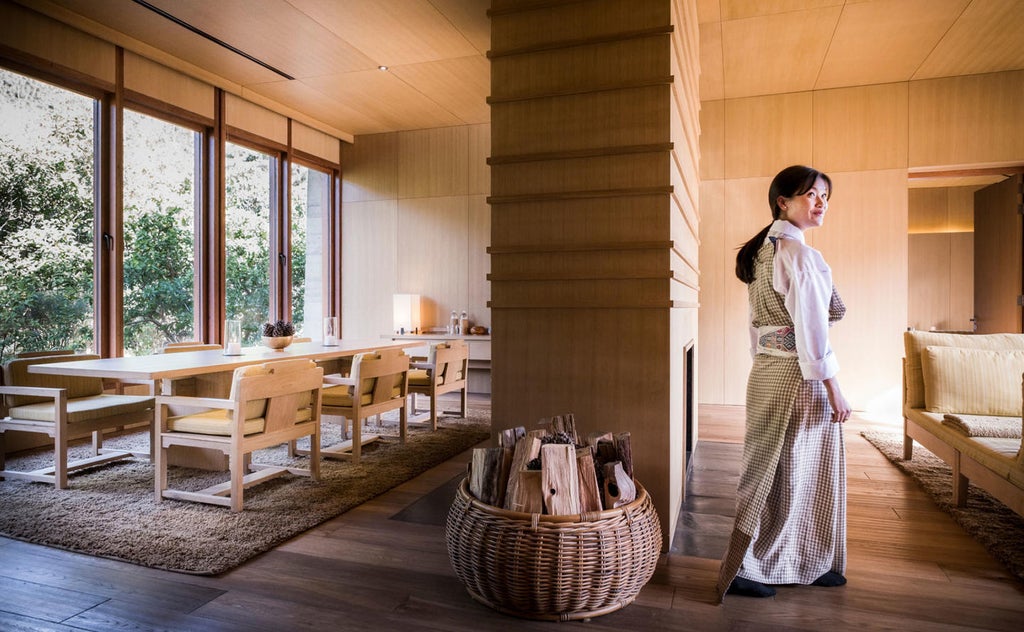 Traditional Bhutanese lodge perched on green hillside with infinity pool overlooking lush Punakha valley and terraced rice fields