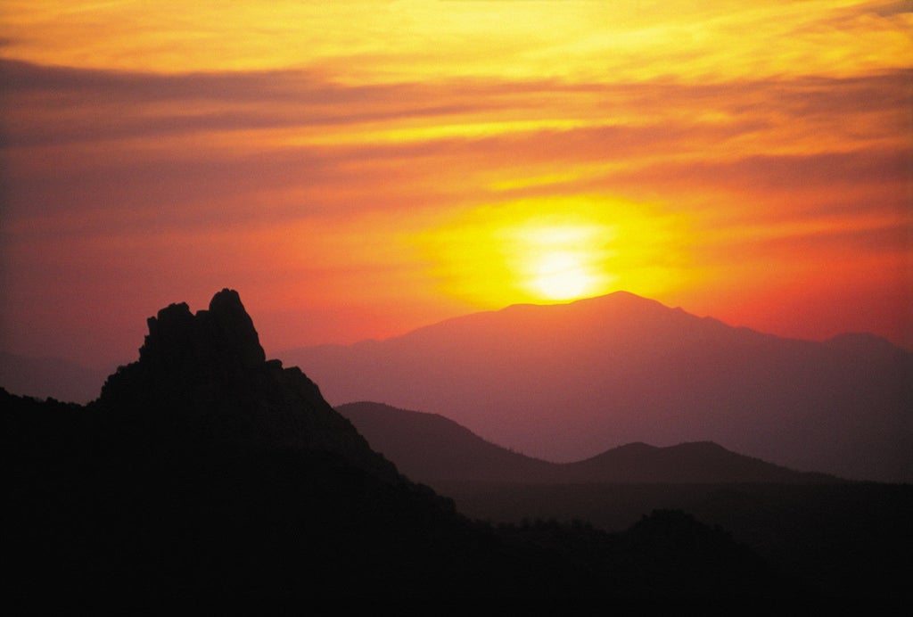 Modern adobe-style luxury resort amid red rock formations, with elegant pools and palm trees in a Sonoran Desert landscape at sunset