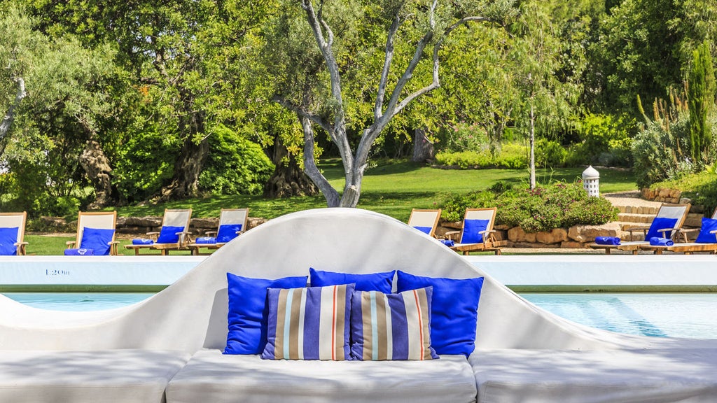 Elegant white Portuguese villa with infinity pool overlooking serene countryside, terracotta roofs nestled among lush gardens at sunset