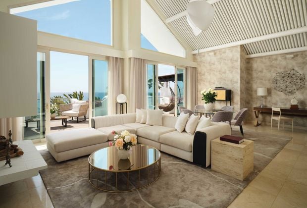 Luxurious Mediterranean-style hotel room with elegant furnishings, warm wood tones, and panoramic view of coastal landscape at Puente Romano Resort, Marbella.