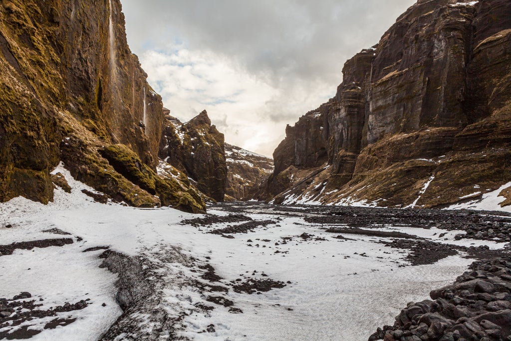 Rugged superjeep traversing volcanic landscape in Thórsmörk, Iceland, with dramatic green mountains and moss-covered terrain in background