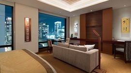 Elegant Tokyo hotel room with panoramic city views, minimalist design, modern furnishings, and floor-to-ceiling windows showcasing urban landscape.