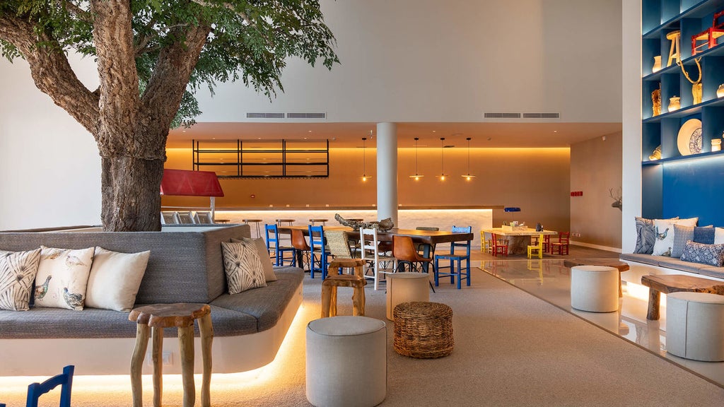 White modern luxury hotel building with large glass windows, set against clear blue skies and surrounded by cork oak trees in rural Portugal.