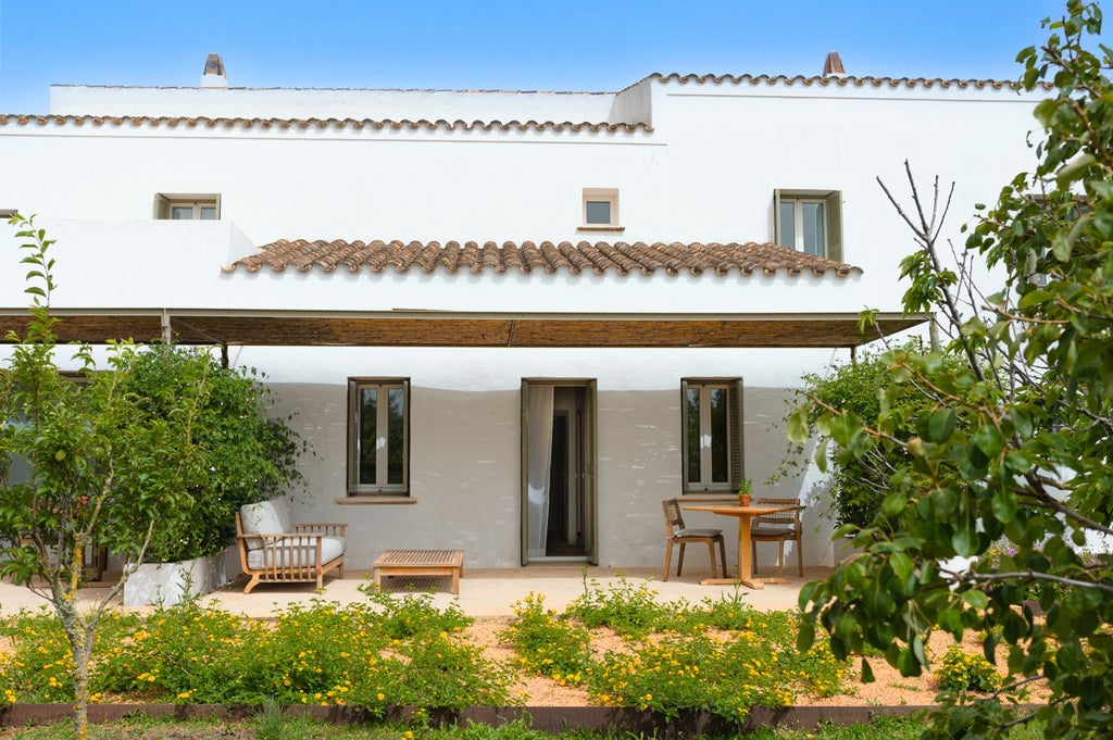 Luxurious white-walled Spanish hotel room with minimalist design, crisp linens, elegant wooden furniture, and expansive windows overlooking countryside landscape