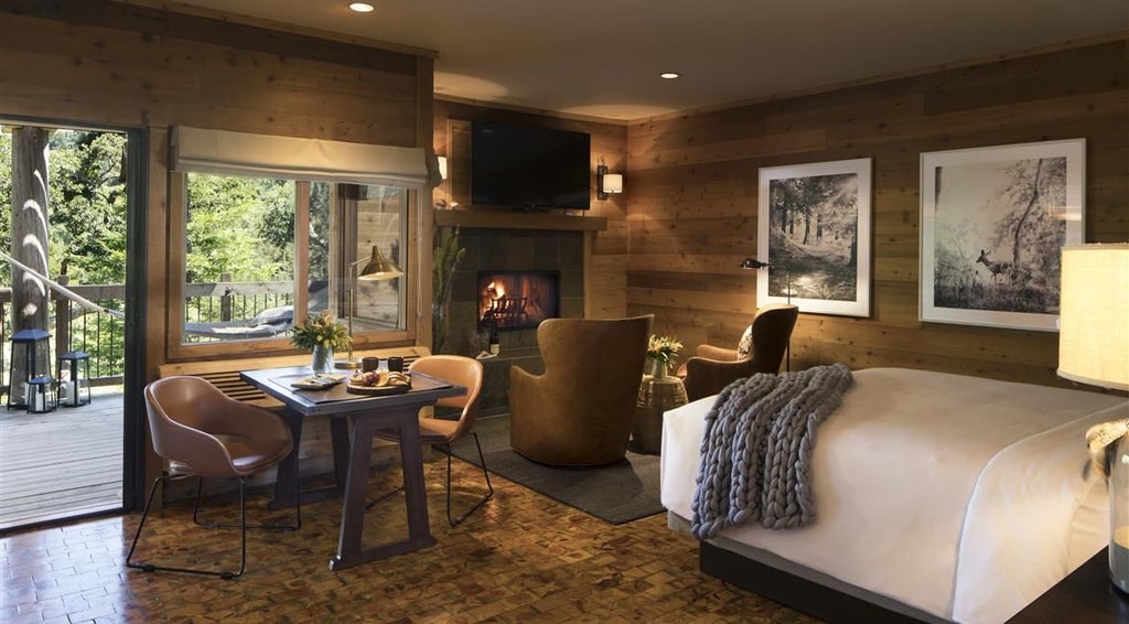 Luxurious Big Sur Suite with panoramic coastal views, elegant wood furnishings, king bed, and large windows framing dramatic Pacific Ocean landscape