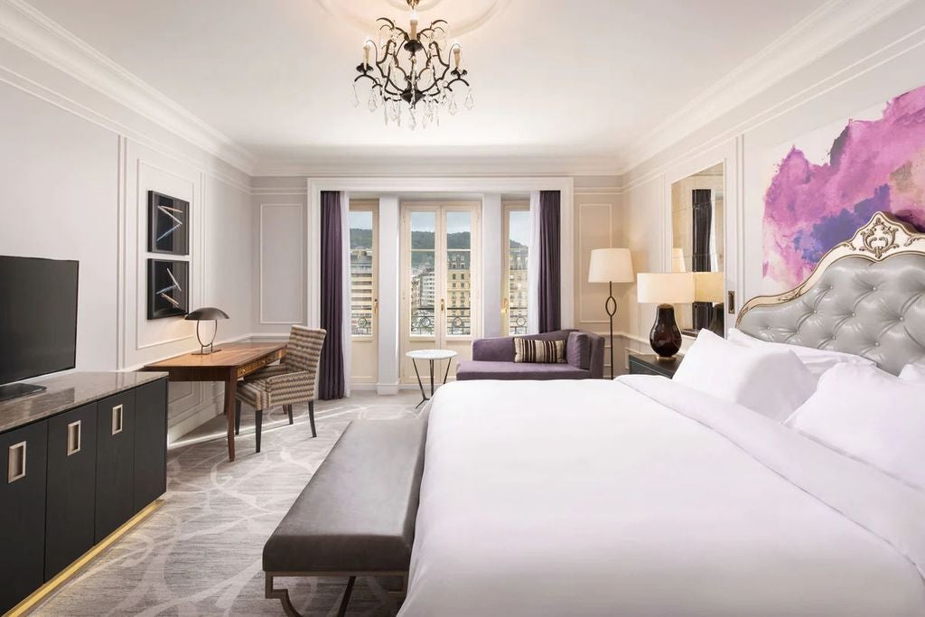 Historic luxury hotel in San Sebastian with elegant white Belle Époque facade, ornate balconies, and grand entrance framed by palm trees