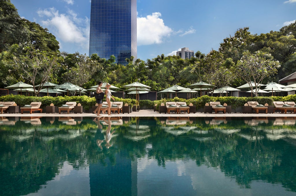 Elegant Thai-style hotel exterior with reflecting pools, traditional pavilions and lush tropical gardens at night illuminated by warm lighting