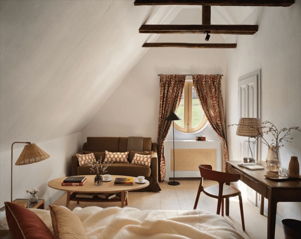 Rustic corner barn suite with exposed wooden beams, plush white bedding, and panoramic views of Transylvanian countryside at Bethlen Estates luxury retreat