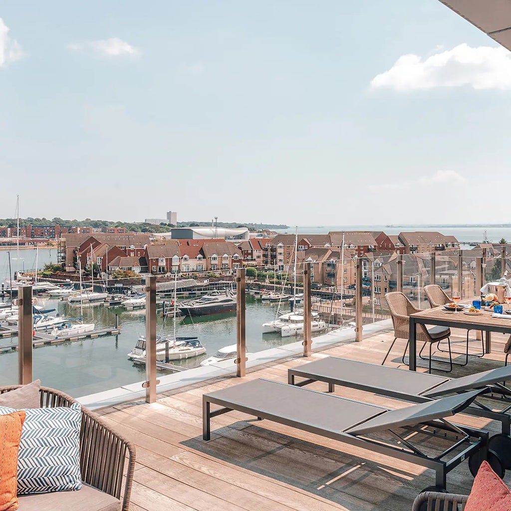 Luxurious Marina View Suite with balcony overlooking Southampton's waterfront, featuring modern decor, floor-to-ceiling windows, and elegant maritime-inspired design