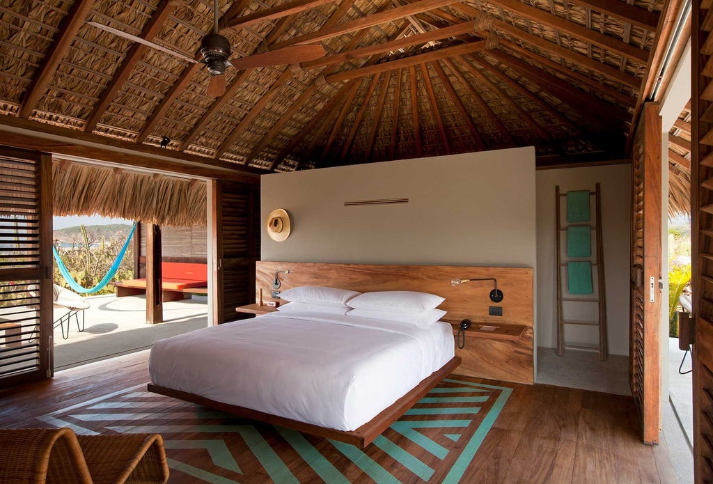 Luxurious white-walled deluxe hotel room with minimalist design, crisp linens, wooden accents, and large windows overlooking scenic Mexican landscape