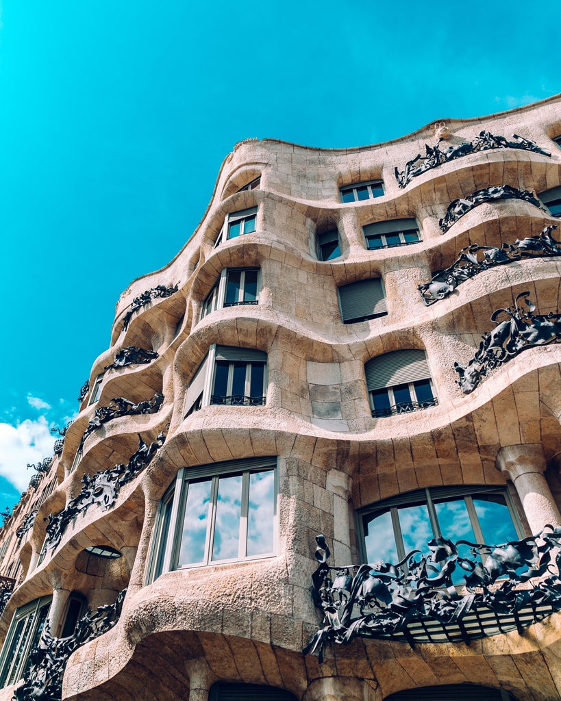 Architectural marvel: Ornate Gaudí masterpiece with intricate stone facade, vibrant mosaic details, and sun-drenched Barcelona skyline in luxurious golden light