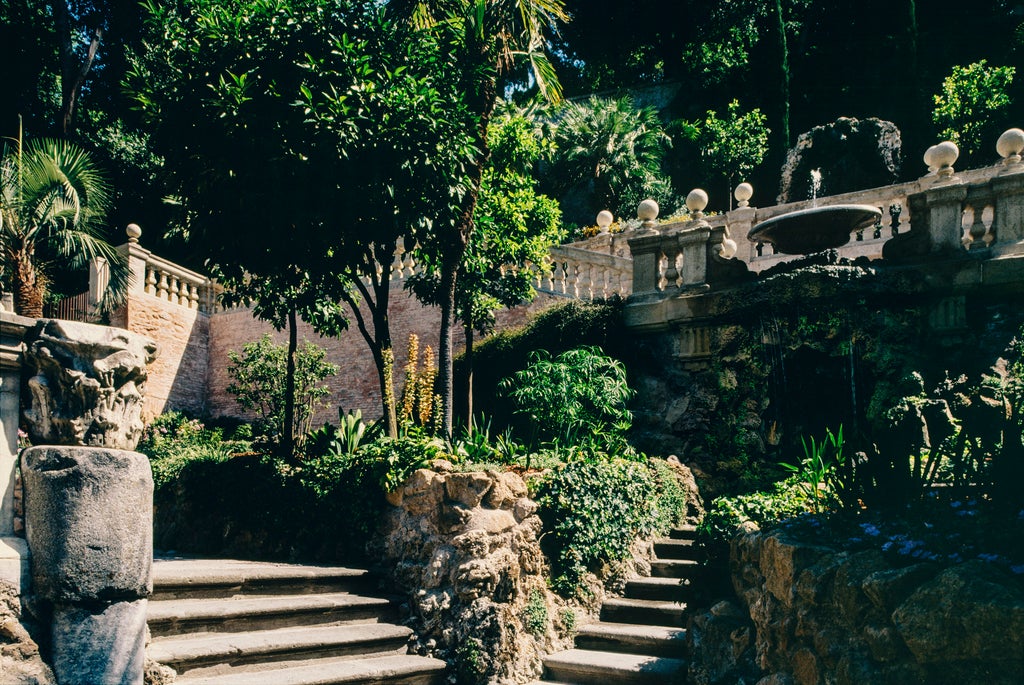 Elegant courtyard at Hotel de Russie Rome, featuring manicured gardens, stone archways and classical Italian architecture at dusk