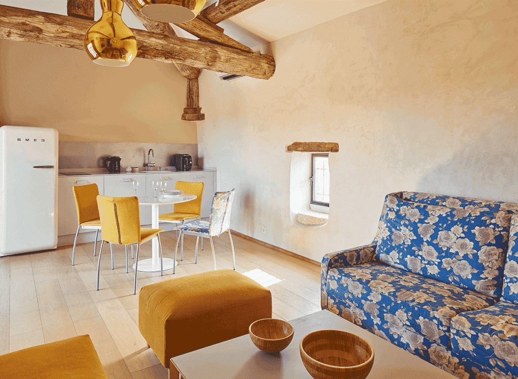 Elegant stone-walled suite with soft blue bedding, antique wooden furniture, and soft natural light in a historic French countryside hotel