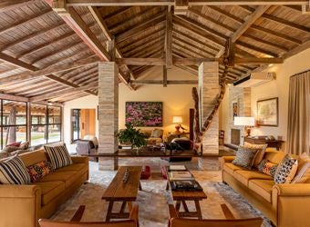 Luxurious private villa bedroom at Caiman Ecological Refuge, featuring elegant decor, crisp white linens, and Brazilian wilderness views through large windows