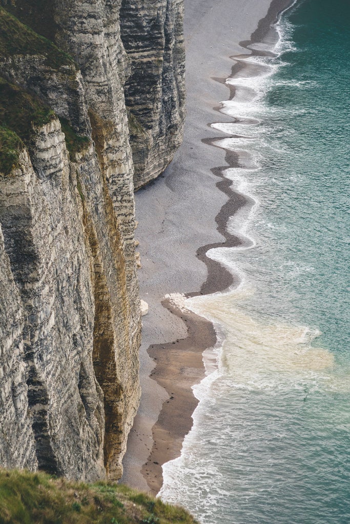 Scenic view of historic World War II memorial at Normandy coastline, with pristine sandy beaches and poignant stone monuments commemorating D-Day landings.