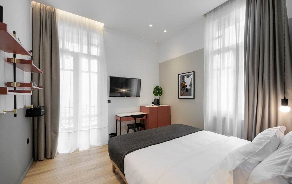 Sleek, minimalist hotel room with clean lines, soft gray color palette, modern furnishings, large window, and elegant urban view of Thessaloniki's cityscape