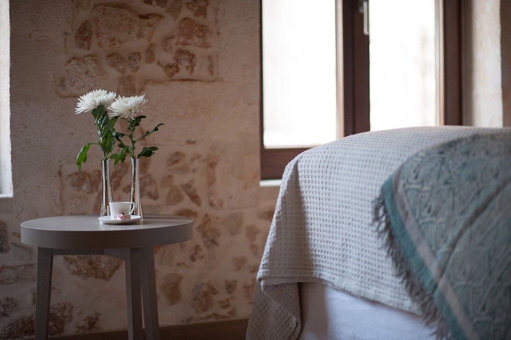 Elegant junior suite with minimalist design, white linens, marble bathroom, and panoramic Aegean Sea view in a luxury boutique hotel in Greece