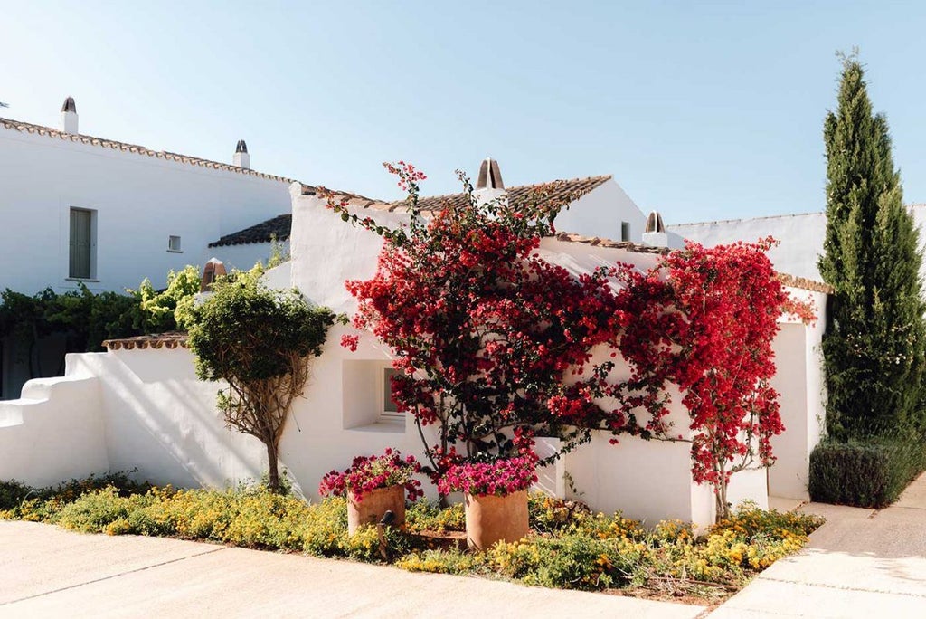 Whitewashed luxury hotel overlooking Menorcan countryside, stone walls, minimalist design, rustic charm meets contemporary elegance amid Mediterranean landscape