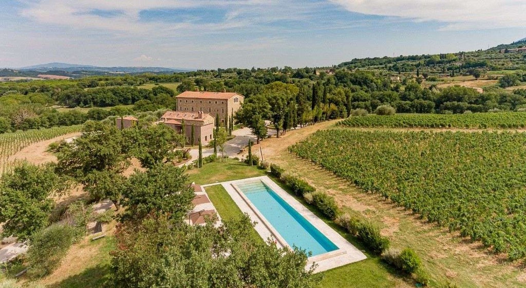 Elegant Mediterranean villa with stone facade, arched windows, and manicured garden featuring a sunlit private swimming pool and terrace