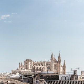 Elegant boutique hotel facade with modernist architecture, white walls, and lush greenery in Palma de Mallorca's historic district