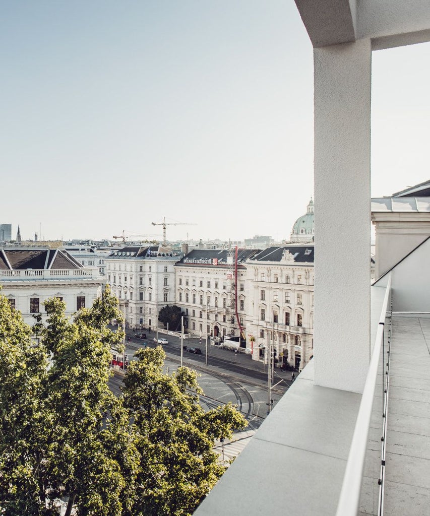 Elegant marble-clad luxury suite with panoramic windows, plush white king bed, and classic Viennese design overlooking Austrian cityscape