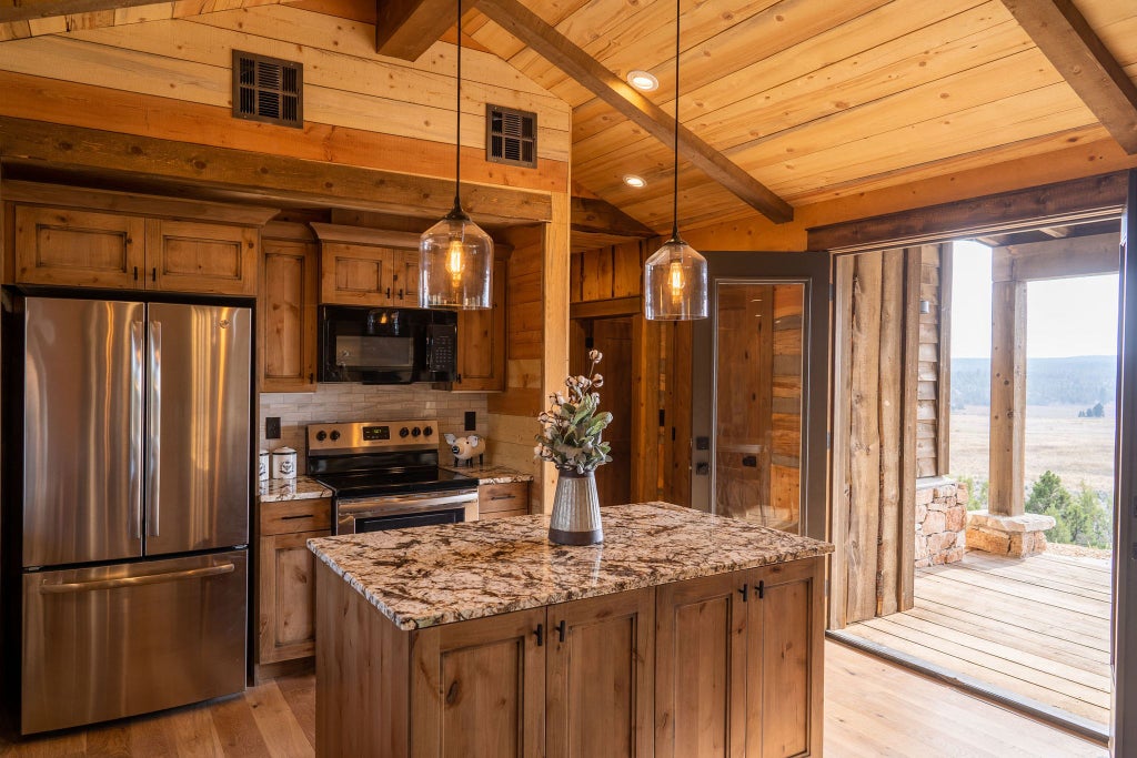 Rustic lodge room with wooden furnishings, plush bedding, and mountain-view windows at Scenset Mountain Ranch in the scenic United States landscape