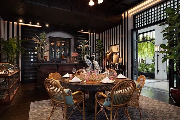 Elegant hotel atrium with black-and-white tiled floor, tropical plants, and Art Deco-inspired columns in monochrome design, Bangkok