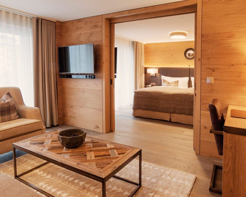 Elegant Swiss Alpine hotel suite with modern wooden furnishings, plush white bedding, large windows revealing mountain landscape, warm neutral color palette