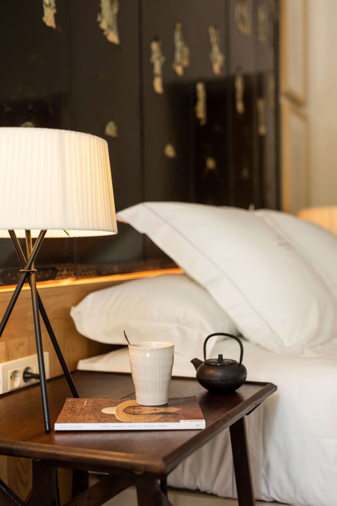 Elegant deluxe hotel room at Margot House, featuring plush white bedding, minimalist decor, and warm natural light in a contemporary Barcelona space