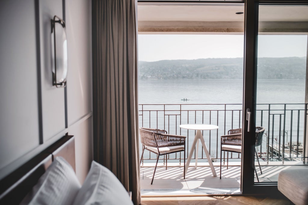 Hotel Alex Lake Zurich's sleek glass exterior reflects on Lake Zurich, featuring modern waterfront terraces and private boat dock at sunset