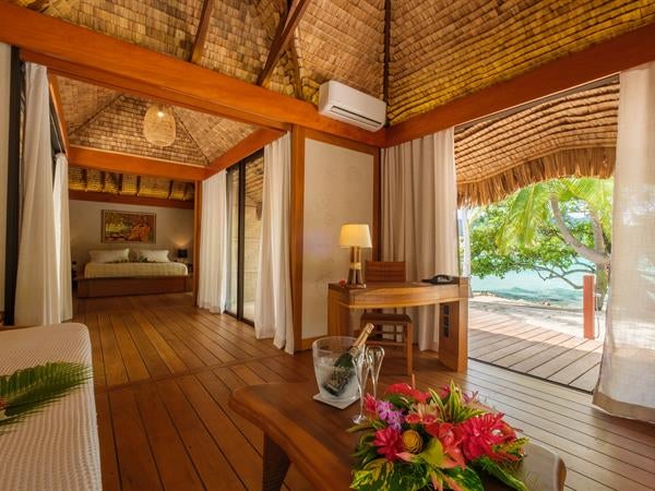 Luxurious overwater villa with private infinity pool overlooking turquoise lagoon, thatched roof, and direct ocean access in Tahaa