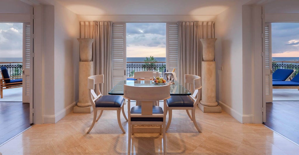 Spacious two-bedroom deluxe suite with modern furnishings, plush king beds, marble bathroom, and panoramic sea view from private balcony in Cyprus hotel