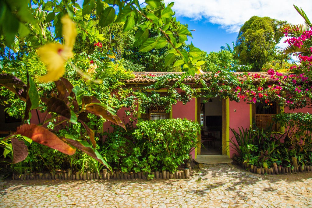 Luxurious eco-chic hotel nestled in lush tropical landscape, rustic wooden buildings blend seamlessly with vibrant Brazilian coastal village setting.