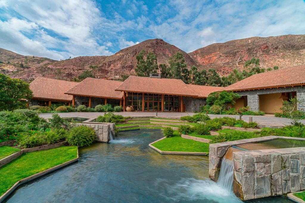 Luxury mountain resort with stone and wood architecture nestled in Sacred Valley, featuring infinity pool overlooking Andean peaks