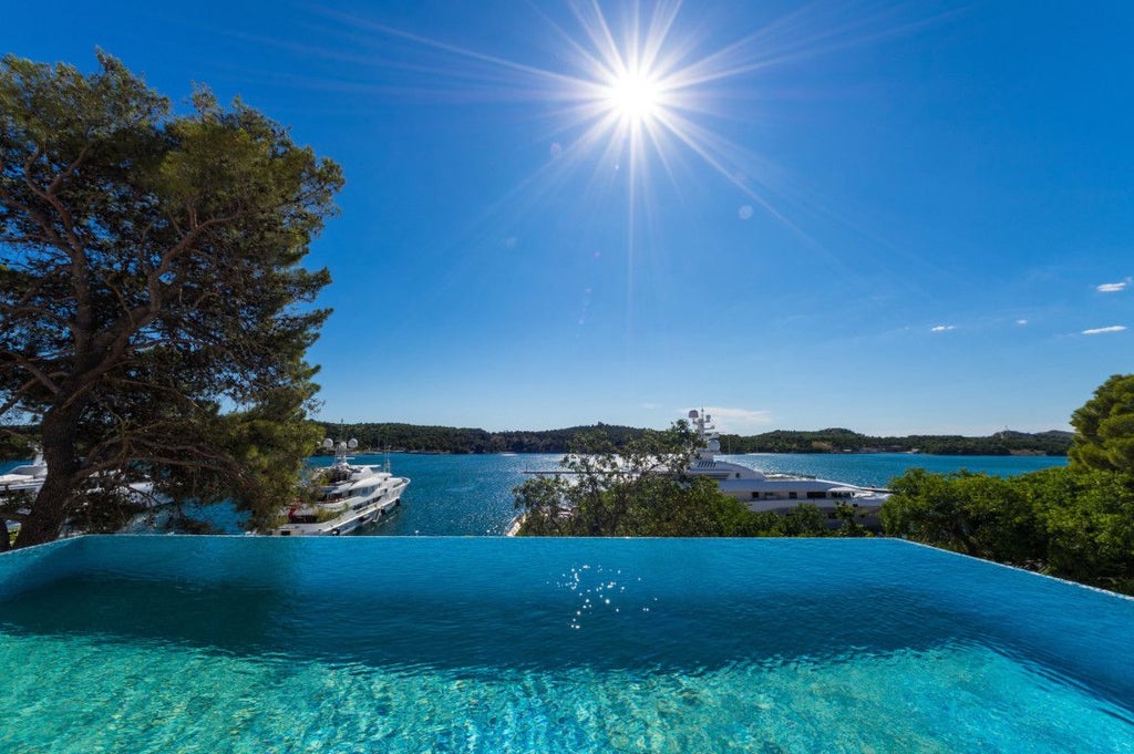 Luxurious waterfront hotel with modern architecture overlooking Šibenik's azure waters, featuring sleek design and panoramic Adriatic Sea views at sunset