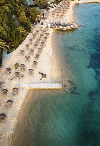 Luxurious beachfront resort with white-washed buildings, blue-domed architecture, and crystal-clear Aegean Sea waters at Scenset Palace Hotel in Halkidiki, Greece.