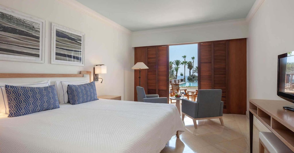 Elegant terrace sea view room at seaside hotel with plush white bedding, sleek modern furnishings, and panoramic Mediterranean coastline vista