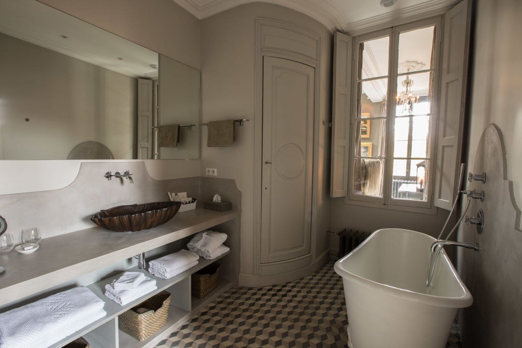 Elegant French hotel suite with ornate baroque ceiling, plush velvet armchair, and soft golden lighting highlighting luxurious cream and gold color palette