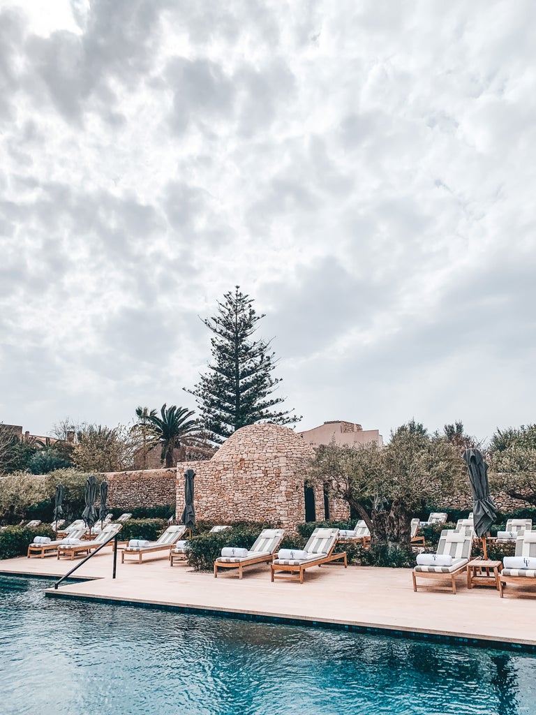 Historic Spanish villa with rustic stone walls, wooden shutters and climbing ivy, set against rich golden hour Mediterranean sunlight