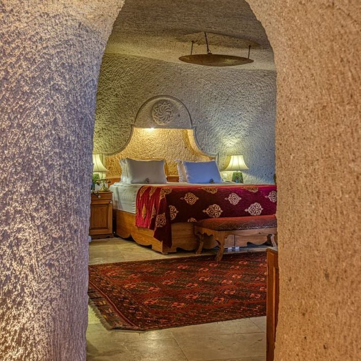 Elegant marble-clad hotel suite with opulent king bed, plush velvet armchairs, and panoramic cityscape view in Museum Hotel's Imperial Suites, Turkey